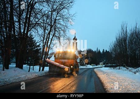 Vista frontale di spazzaneve carrello di servizio - auto gritter spandimento di sale sulla strada. La manutenzione delle strade in inverno in montagna. Foto Stock