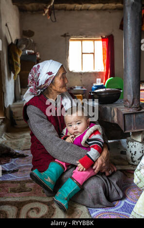 Il bayan Ulgii, Mongolia, 30 Settembre 2015: mongola nomade kazako granmother tenendo un ragazzo sul suo giro all'interno di una casa di inverno Foto Stock