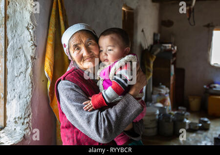 Il bayan Ulgii, Mongolia, 30 Settembre 2015: mongola nomade kazako granmother tenendo un ragazzo sul suo giro all'interno di una casa di inverno Foto Stock