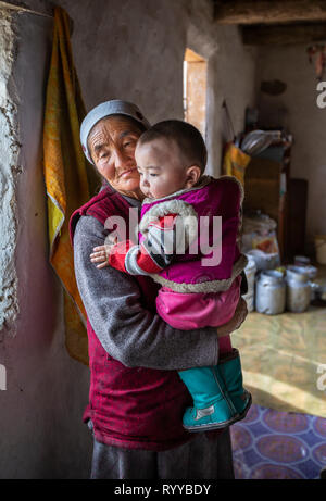 Il bayan Ulgii, Mongolia, 30 Settembre 2015: mongola nomade kazako granmother tenendo un ragazzo sul suo giro all'interno di una casa di inverno Foto Stock