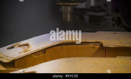 Una macchina CNC in azione utilizzando il foglio di legno a forare il legno per creare un modello del pezzo di legno Foto Stock