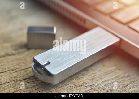 Close up di metallo unità flash USB collegato al laptop sulla scrivania di legno Foto Stock