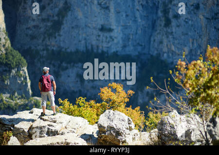 Giovane maschio esplorando turistica di Vikos nel Pindo della Grecia settentrionale, adagiata sulle pendici meridionali del Monte Tymfi, uno dei più profondi g Foto Stock