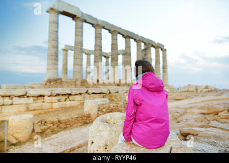 Carino giovane ragazza ad esplorare il Greco antico tempio di Poseidone a Capo Sounion, uno dei principali monumenti di età d'Oro di Atene. Foto Stock