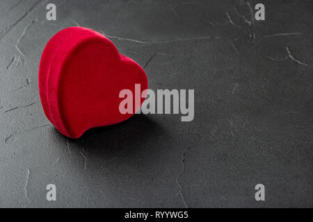 Casella rossa per gli anelli a forma di cuore su uno sfondo di calcestruzzo Foto Stock