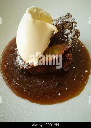 Pera e zenzero torta con clotted cream e toffee salsa. Foto Stock