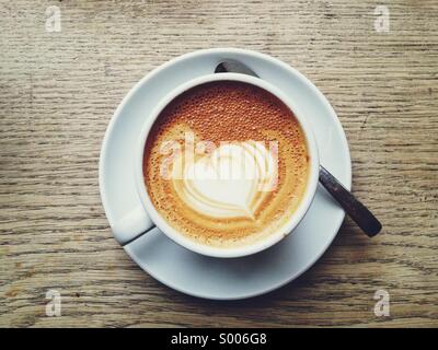 A forma di cuore ad arte del caffè su una tazza di latte Foto Stock