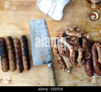 Barbecue con salsicce vegetariane e reale la salsiccia di carne, separati da una mannaia Foto Stock