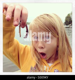 Una ragazza in luce gli occhi mentre si sta guardando un squirmy crawly usurati. Foto Stock