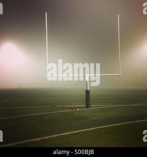 Campo di calcio e goal post avvolto nella nebbia di notte Foto Stock