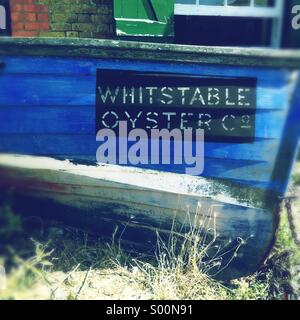 Un weathered barca a remi visualizza il nome di Whitstable Oyster Company a Whitstable, Kent, Regno Unito. Foto Stock