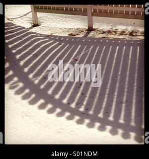 L ombra di una recinzione sulla neve in basso sole invernale... Foto Stock