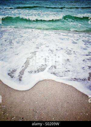 Ocean wave rottura sulla riva sabbiosa presso il st. Pete's Beach sul Golfo del Messico in Florida Foto Stock