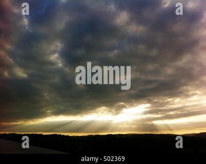 Raggi di sole tra le nuvole al tramonto Foto Stock