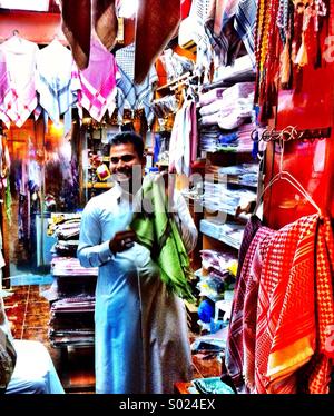 Panno sorridente venditore nel Souk arabo invita i propri clienti a ispezionare la sua merce Foto Stock