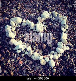 Un cuore di pietre bianche e ciottoli su una pittoresca spiaggia Foto Stock