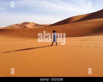 Uomo vestito con abiti tradizionali è in marcia nel deserto Foto Stock