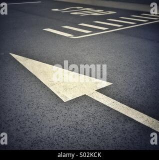 Dipinto di bianco freccia e stop sulla strada Foto Stock