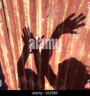 Madre e figlia delle ombre sulla recinzione Foto Stock