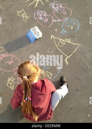 Bambino disegna con un gessetto su asfalto Foto Stock