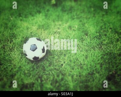 Vecchio calcio, deflazionato sull'erba. Grunge e tilt-shift gli effetti applicati. Foto Stock