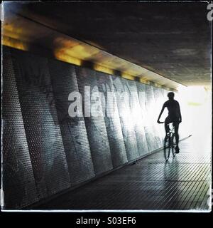 Silhouette di una bici attraverso un sottopassaggio buio che simboleggia la luce alla fine del tunnel Foto Stock