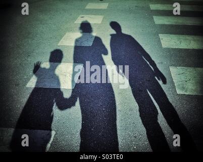 Ombra di una famiglia in attesa in un attraversamento pedonale Foto Stock