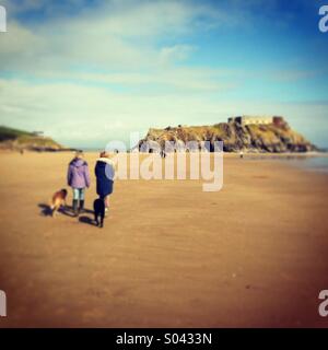 Due donne che camminano con i cani sulle sabbie della bassa marea della spiaggia di Tenby, Regno Unito. Foto per iPhone in stile Instagram. Foto Stock