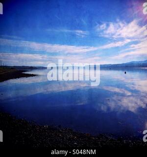 Nuvole riflettono in Stretto di Menai da Anglesey Foto Stock