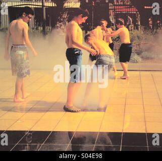 Ragazzi adolescenti giocando in una fontana Foto Stock