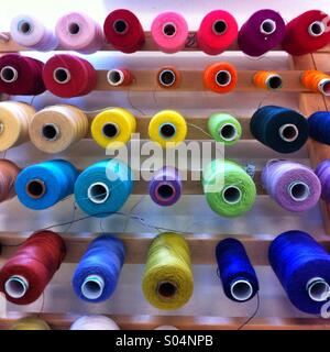 Bobine di cotone colorato thread su un rack di legno Foto Stock