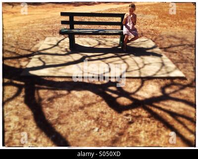 Bambina su una panchina nel parco. Foto Stock