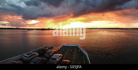 Una vista panoramica da un imbuto rosso traghetto per l'Isola di Wight durante il tramonto su Southampton acqua. Fawley raffineria di petrolio è visibile sulla sinistra dell'inquadratura Foto Stock