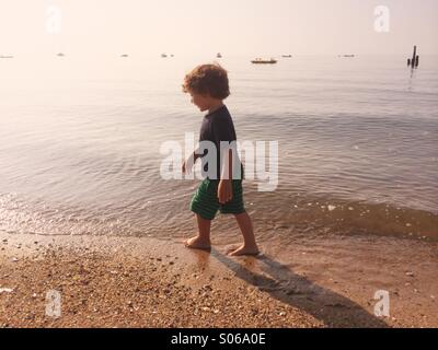 Un piccolo ragazzo giocando su una spiaggia assolata durante l estate in Connecticut, Stati Uniti d'America. Foto Stock