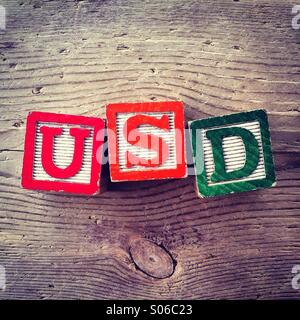Si tratta di una foto di tavolette di legno giocattolo giochi con alfabeto lettere su di essi che si combinano insieme per formare l'acronimo di USD per dollaro degli Stati Uniti Foto Stock
