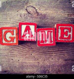 Si tratta di una foto di tavolette di legno giocattolo giochi con alfabeto lettere su di loro che si uniscono per formare la parola gioco Foto Stock