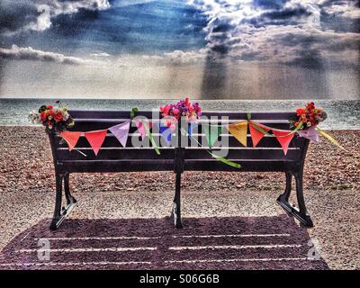 Panca su lungomare decorato con fiori e pavese Foto Stock