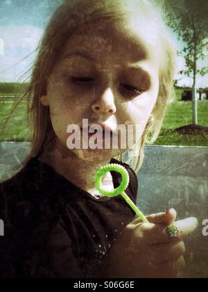 Una ragazza che gioca con le bolle. Foto Stock