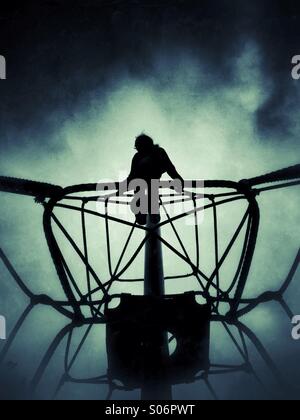 Ragazza sul telaio di arrampicata in silhouette Foto Stock