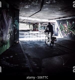 Silhouette di una bici attraverso un sottopassaggio buio che simboleggia la luce alla fine del tunnel Foto Stock