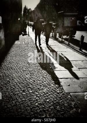 Retroilluminato con gli uomini e le loro ombre, camminando verso il fotografo Foto Stock