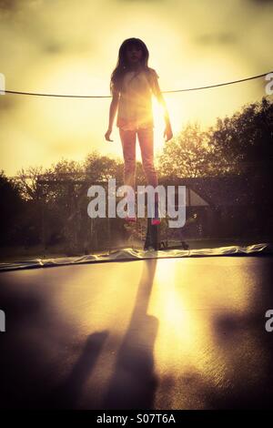 Lancio. Una giovane ragazza che rimbalza su un giardino trampolino - sollevare - dispari quotidiana Foto Stock