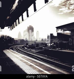 Grattacieli nella città di Londra si vede nella distanza, dal punto di vista della piattaforma a Hoxton overground stazione su una leggermente torbida giorno, in bianco e nero Foto Stock