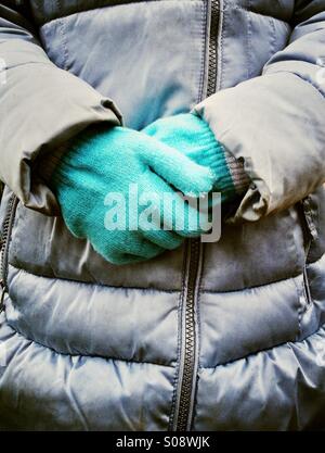 Ragazza giovane con mani guantate tenuto di fronte a lei Foto Stock