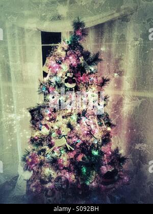 Grungy albero di Natale con luci luminose e ornamenti in salotto Foto Stock