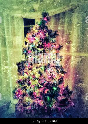 Textured grungy albero di Natale con luci colorate e ornamenti in salotto Foto Stock