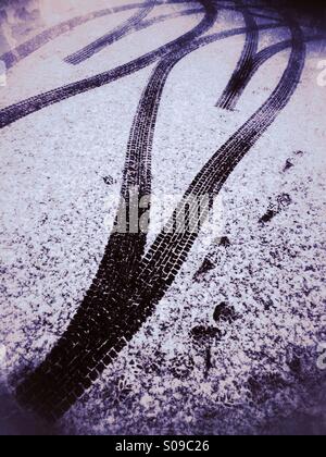 Tracce di pneumatici formando una doppia forma di cuore sulla strada coperta di neve. Foto Stock