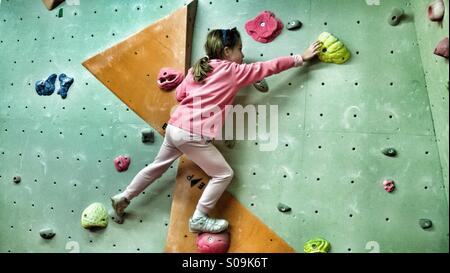 8 anno vecchia ragazza di arrampicata in bouldering camera presso arrampicate indoor center. Foto Stock