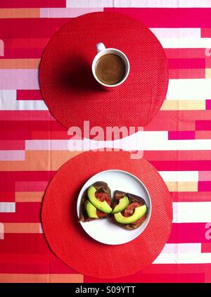 Colazione vegana sul rosso tovaglia geometrica con caffè e panini aperto Foto Stock