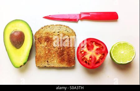 Realizzazione di una Vegana Vegetariana/sandwich aperto con avocado, pomodoro e pane integrale tostato. Foto Stock